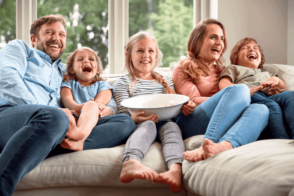 Afbeelding gezin op de bank met een bak popcorn kijkend naar de tv