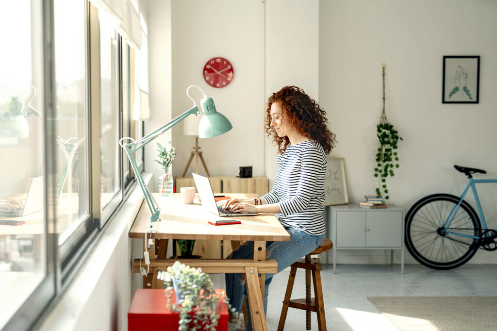 Vrouw werkt thuis achter haar bureau en typt op haar laptop