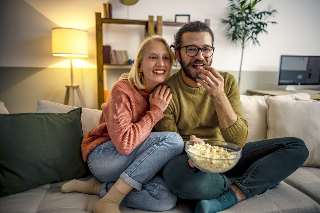 Koppel kijkt tv op de bank met popcorn