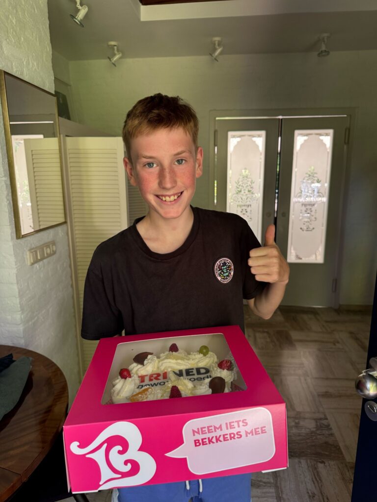 Jongen met de ontvangen taart met het TriNed logo erop.