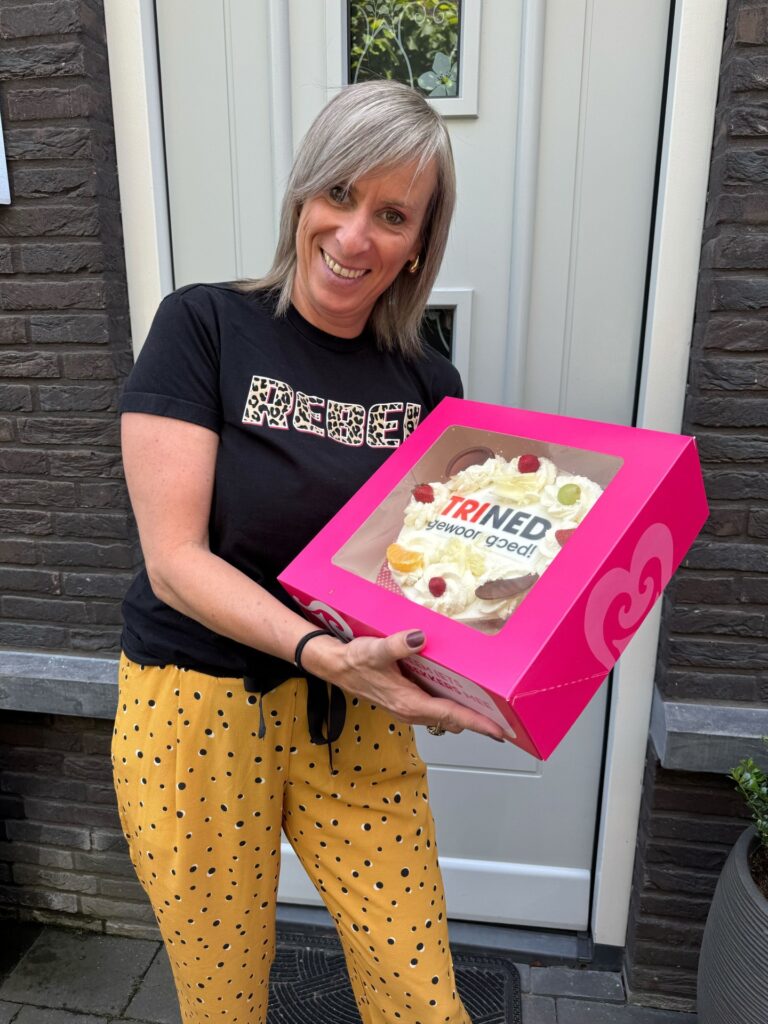 Dame met de ontvangen taart met het TriNed logo erop.