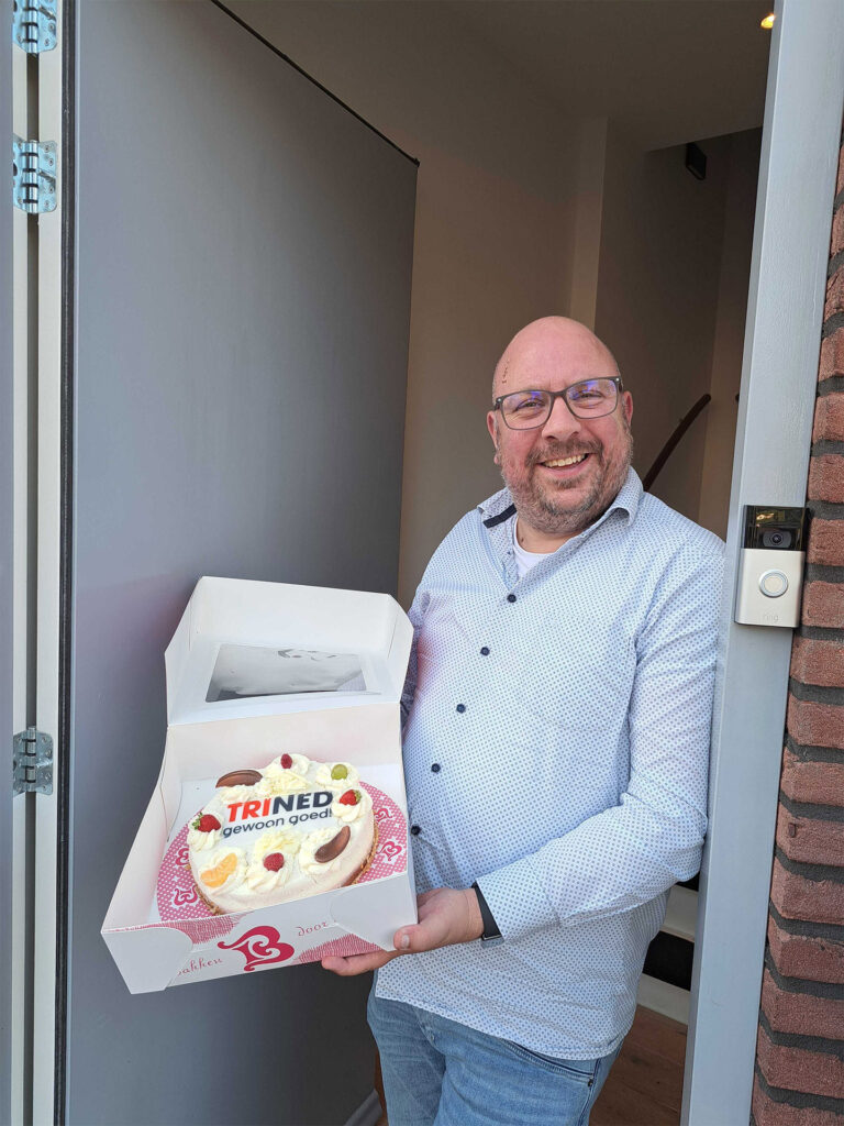 Man met de ontvangen taart met het TriNed logo erop.