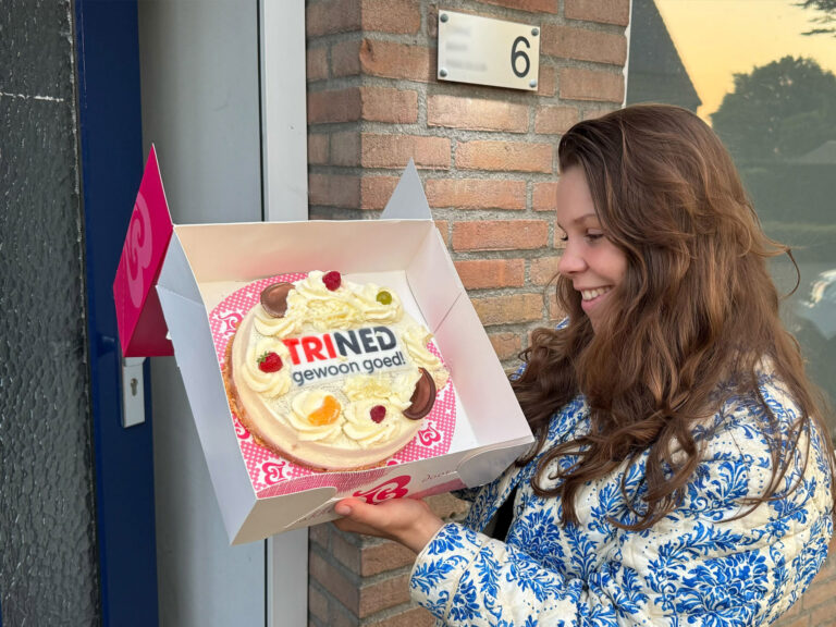 Dame met de ontvangen taart met het TriNed logo erop.