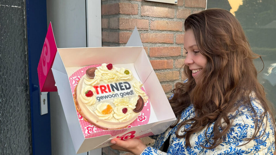 Dame met de ontvangen taart met het TriNed logo erop.